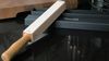 
                    Strop with three strips of leather having different degress of diamond pastes; the fourth without diamond paste is for polish and care